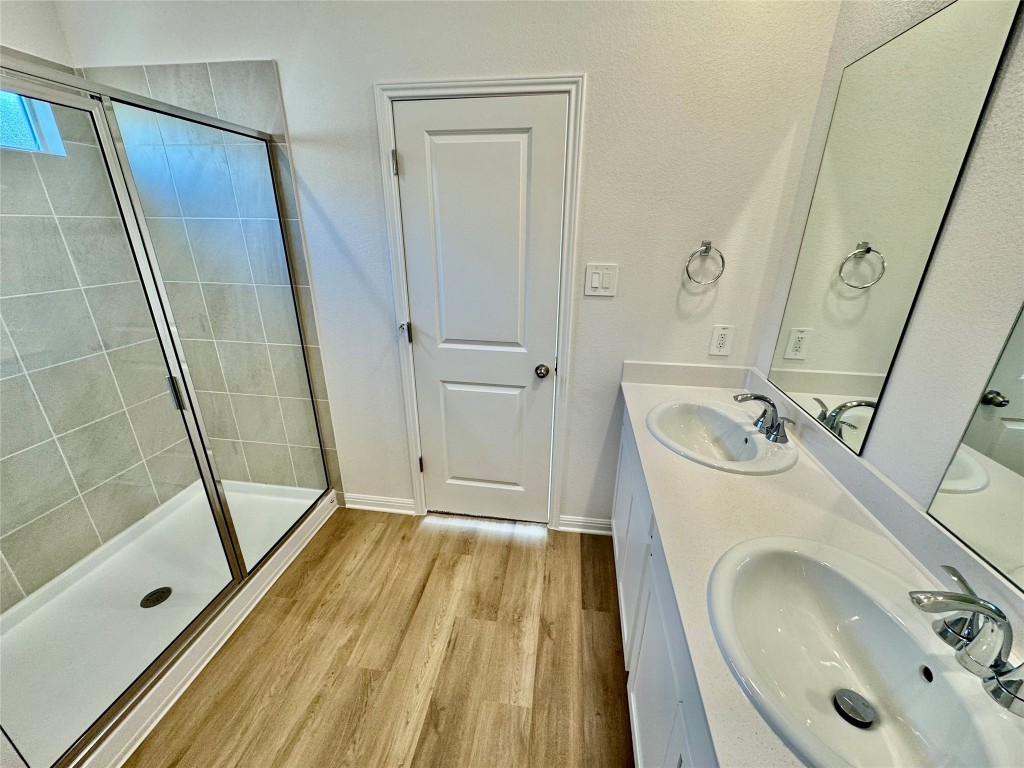 298 Texas Agate Drive Kyle, TX 78640 - Photo 4 of 7 Full bath with double vanity, a stall shower, and light wood finished floors