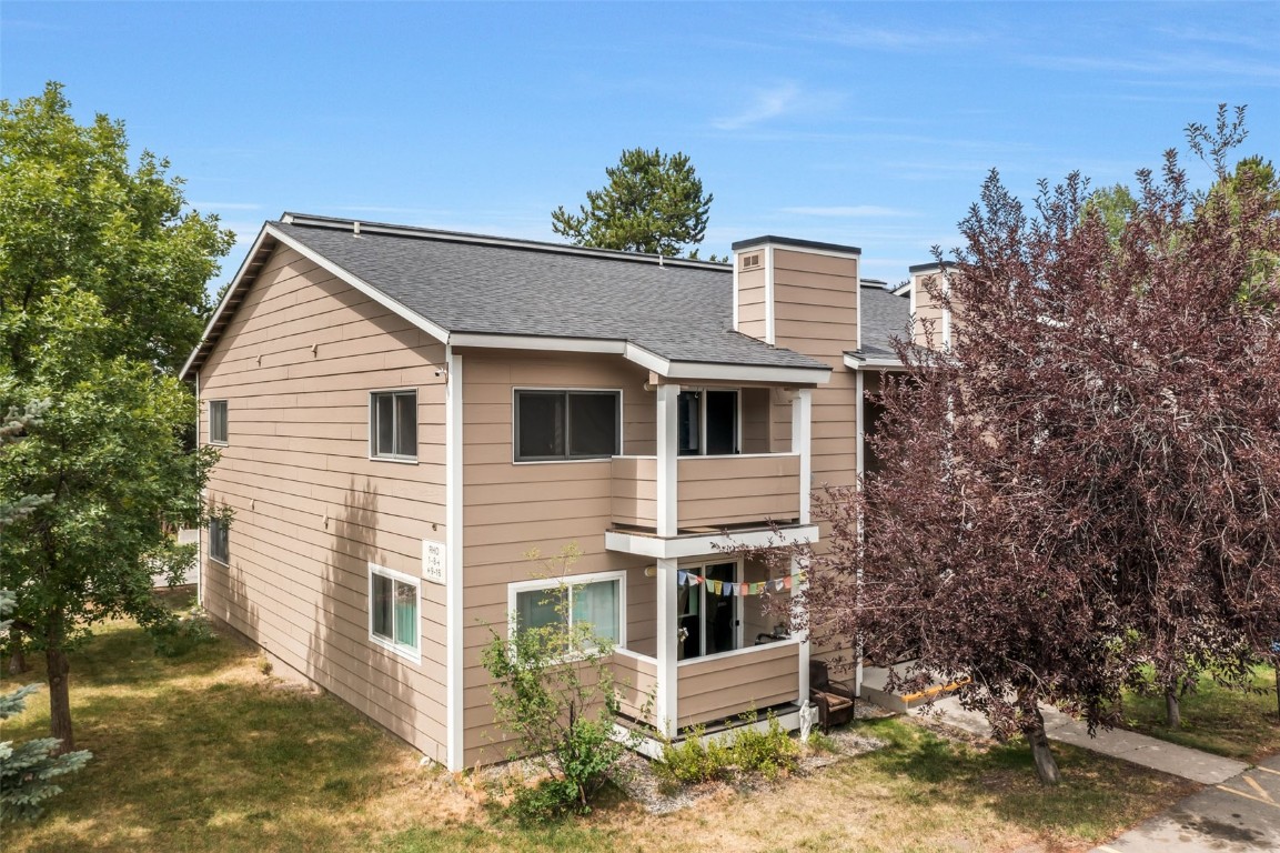 a view of a white house with large windows and wooden fence