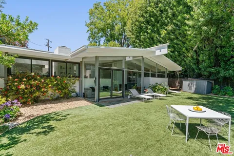 a view of a chair and table in backyard of the house