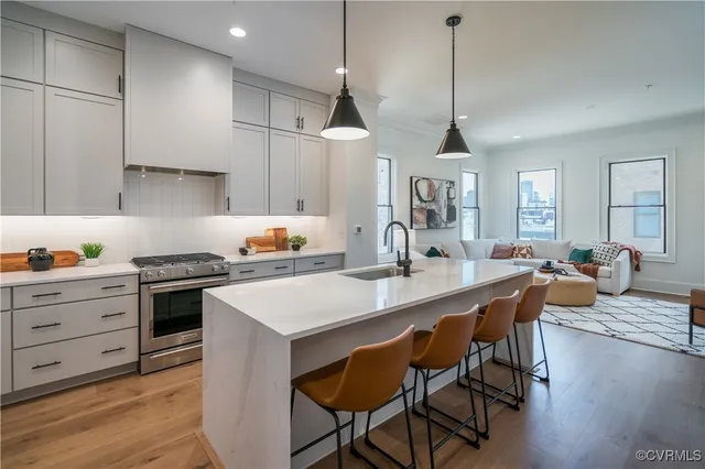 a kitchen with stainless steel appliances granite countertop a sink a stove a refrigerator and wooden floor