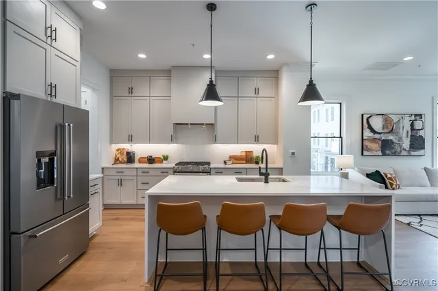 a kitchen with stainless steel appliances granite countertop a sink a stove a refrigerator and chairs