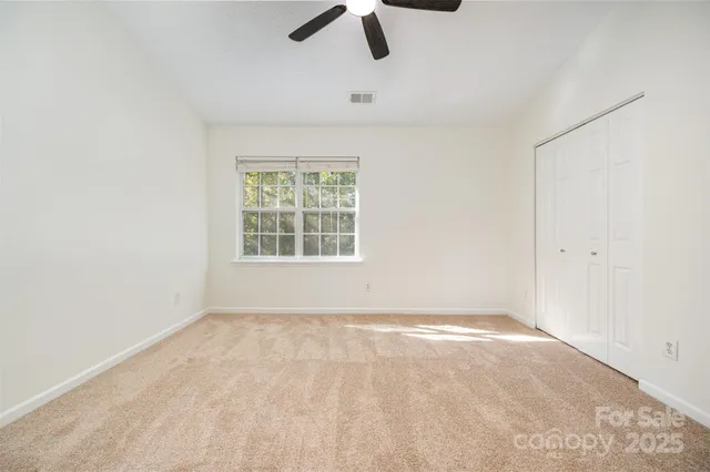 an empty room with ceiling fan and window