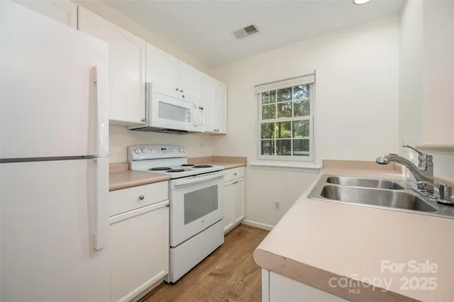 a kitchen with white cabinets and white appliances