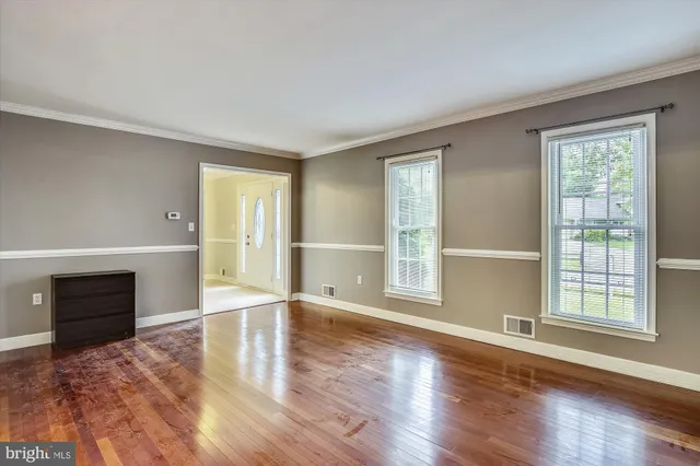 a view of an empty room with a window and wooden floor