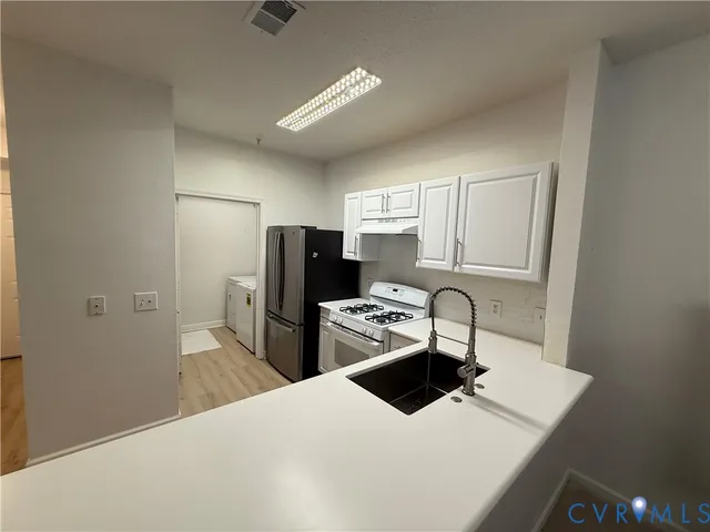 a kitchen with a refrigerator sink and cabinets