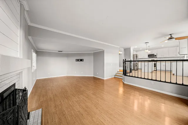 a view of an empty room with chandelier fan and a window