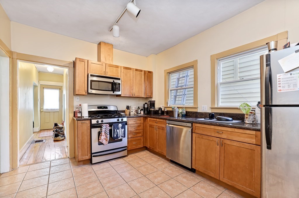 24-26 Crescent Street Cambridge, MA 02138 - Photo 25 of 36 a kitchen with stainless steel appliances granite countertop a stove top oven a sink dishwasher a dining table and chairs with wooden floor