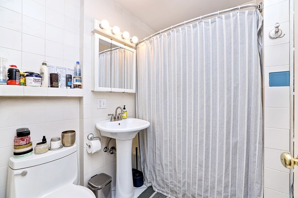 24-26 Crescent Street Cambridge, MA 02138 - Photo 29 of 36 a bathroom with a sink a toilet and shower curtain