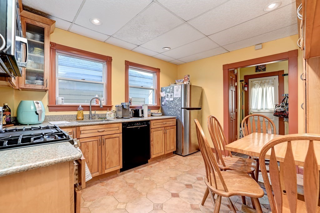 24-26 Crescent Street Cambridge, MA 02138 - Photo 5 of 36 a kitchen with stainless steel appliances granite countertop a stove a sink dishwasher a dining table and chairs with wooden floor