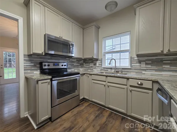 a kitchen with stainless steel appliances granite countertop a stove microwave and sink