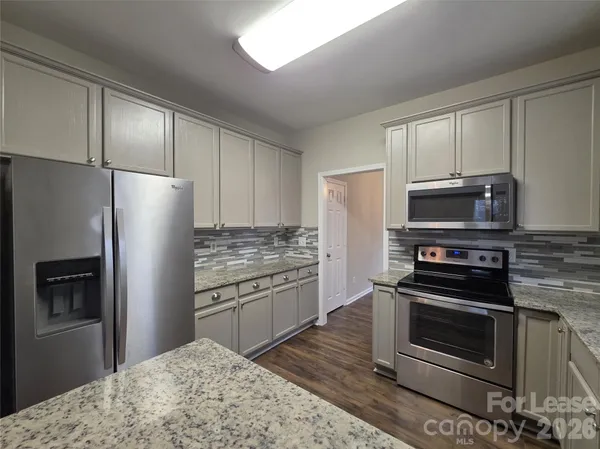 a kitchen with granite countertop a refrigerator stove and microwave