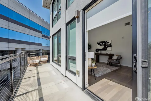 a living room with stainless steel appliances furniture a rug and a view of kitchen