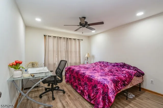 a bedroom with a bed a desk and chair with wooden floor