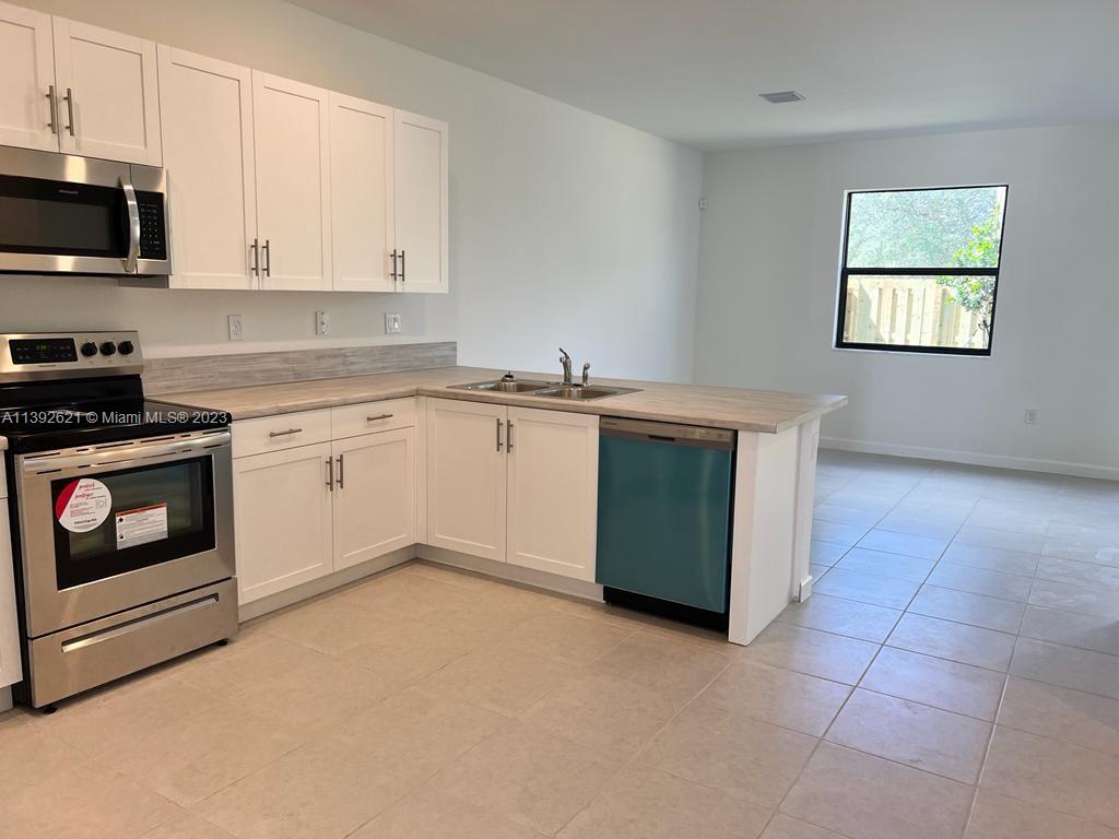 Miami-Dade County Homestead, FL 33032 - Photo 4 of 41 a kitchen with stainless steel appliances granite countertop a stove a sink and a microwave