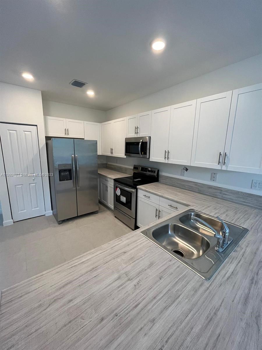 Miami-Dade County Homestead, FL 33032 - Photo 9 of 41 a kitchen with stainless steel appliances a stove a sink and a refrigerator