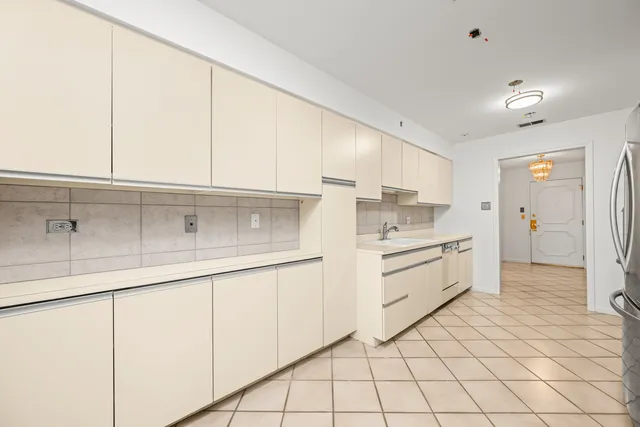 a view of a refrigerator in kitchen and an empty room