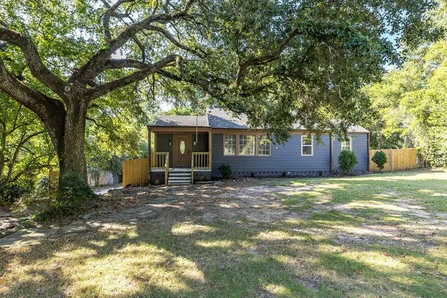 a view of a house with a yard and large tree