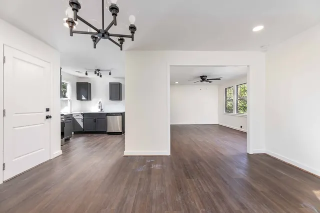 a view of a big room with wooden floor a ceiling fan and windows