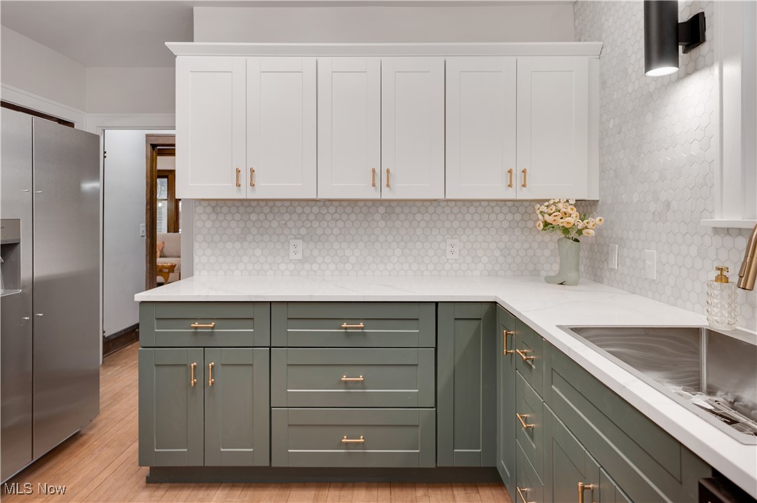 2016 Rossmoor Road Cleveland Heights, OH 44118 - Photo 18 of 46 Kitchen featuring stainless steel fridge with ice dispenser, white cabinets, light stone counters, decorative backsplash, and green cabinets