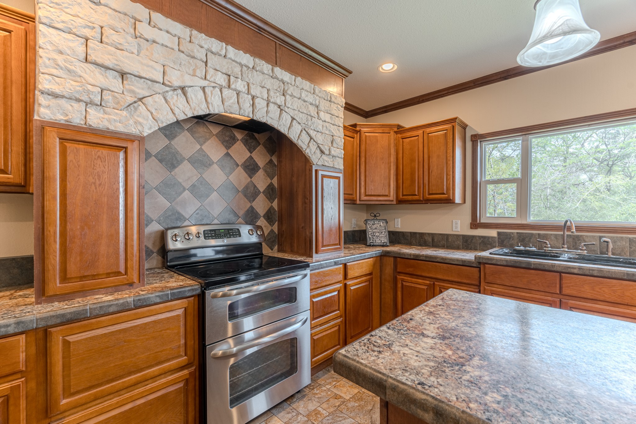115 Canadian Drive Trinity, TX 75862 - Photo 10 of 42 Modern stainless steel stove, tiled backsplash, and ample counter space. A large window provides natural light and a view outside, enhancing the inviting atmosphere.