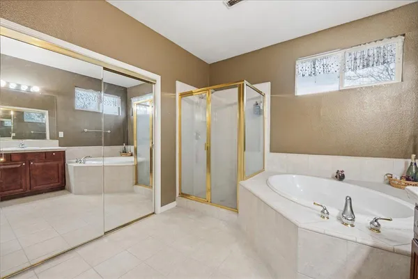 a bathroom with a tub a sink and a large mirror