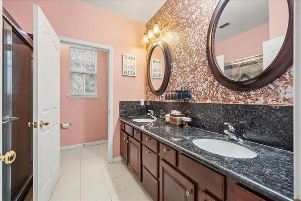 a bathroom with a granite countertop double vanity sink and a mirror