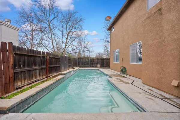 a view of house with backyard and trees in the background