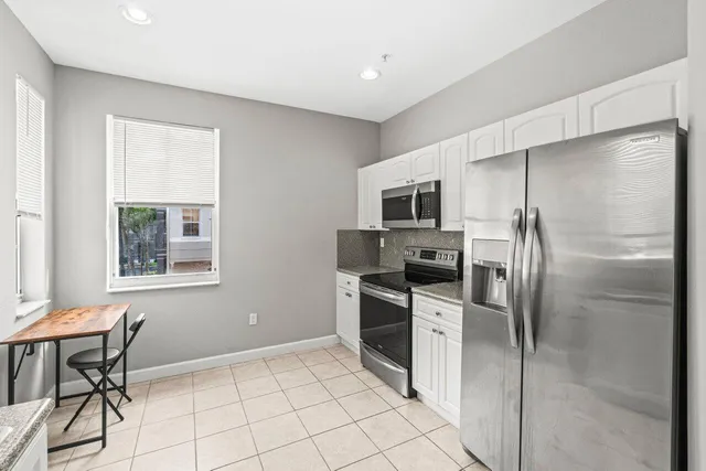 a kitchen with stainless steel appliances granite countertop white cabinets a refrigerator and a stove top oven
