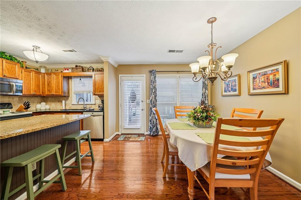 4166 Oakwood Way Duluth, GA 30096 - Photo 5 of 28 a view of a dining room with furniture a chandelier and wooden floor