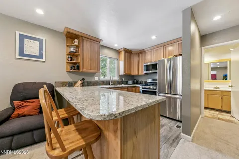 a kitchen with stainless steel appliances granite countertop a refrigerator a sink dishwasher a stove and white countertops with wooden floor