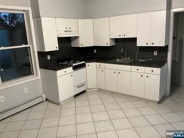 a kitchen with granite countertop a sink a stove and cabinets