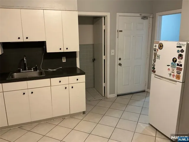 a kitchen with white cabinets and refrigerator
