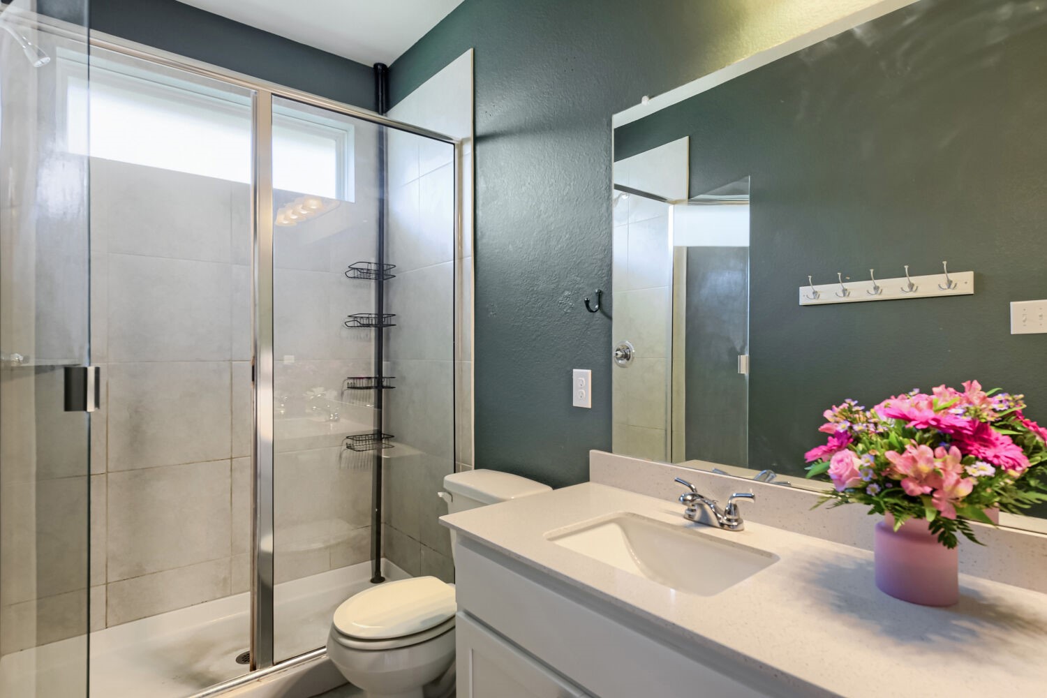1310 Goforth Road Kyle, TX 78640 - Photo 16 of 24 Bathroom featuring a glass-enclosed shower with light tile surround, a white vanity with an integrated sink, a light-toned countertop, and a large wall-mounted mirror