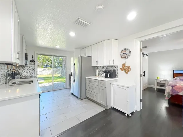 a kitchen with a sink dishwasher a stove and white cabinets with wooden floor