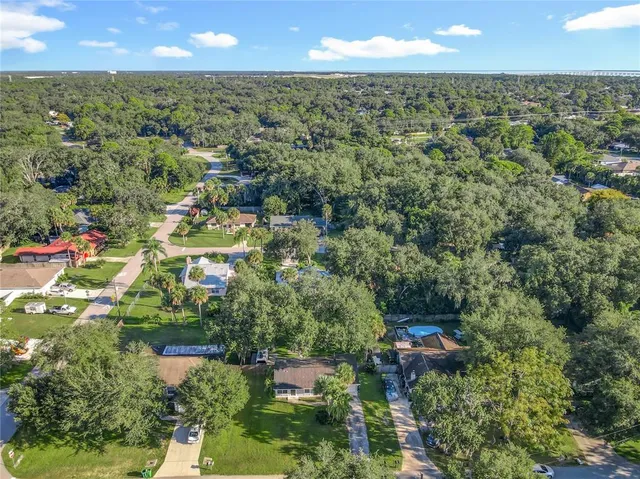 an aerial view of residential houses with outdoor space and trees