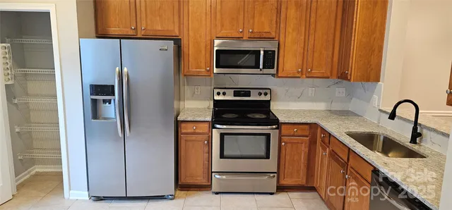 a kitchen with stainless steel appliances granite countertop a refrigerator stove and sink