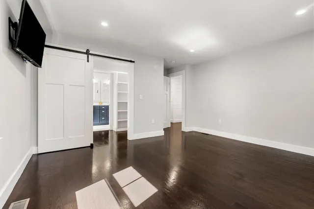a view of an empty room with wooden floor and a flat screen tv