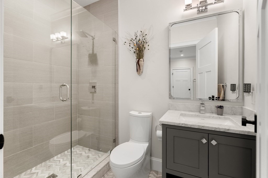 15 Parker Road Needham, MA 02494 - Photo 14 of 41 a bathroom with a toilet a sink a glass door a shower and a mirror