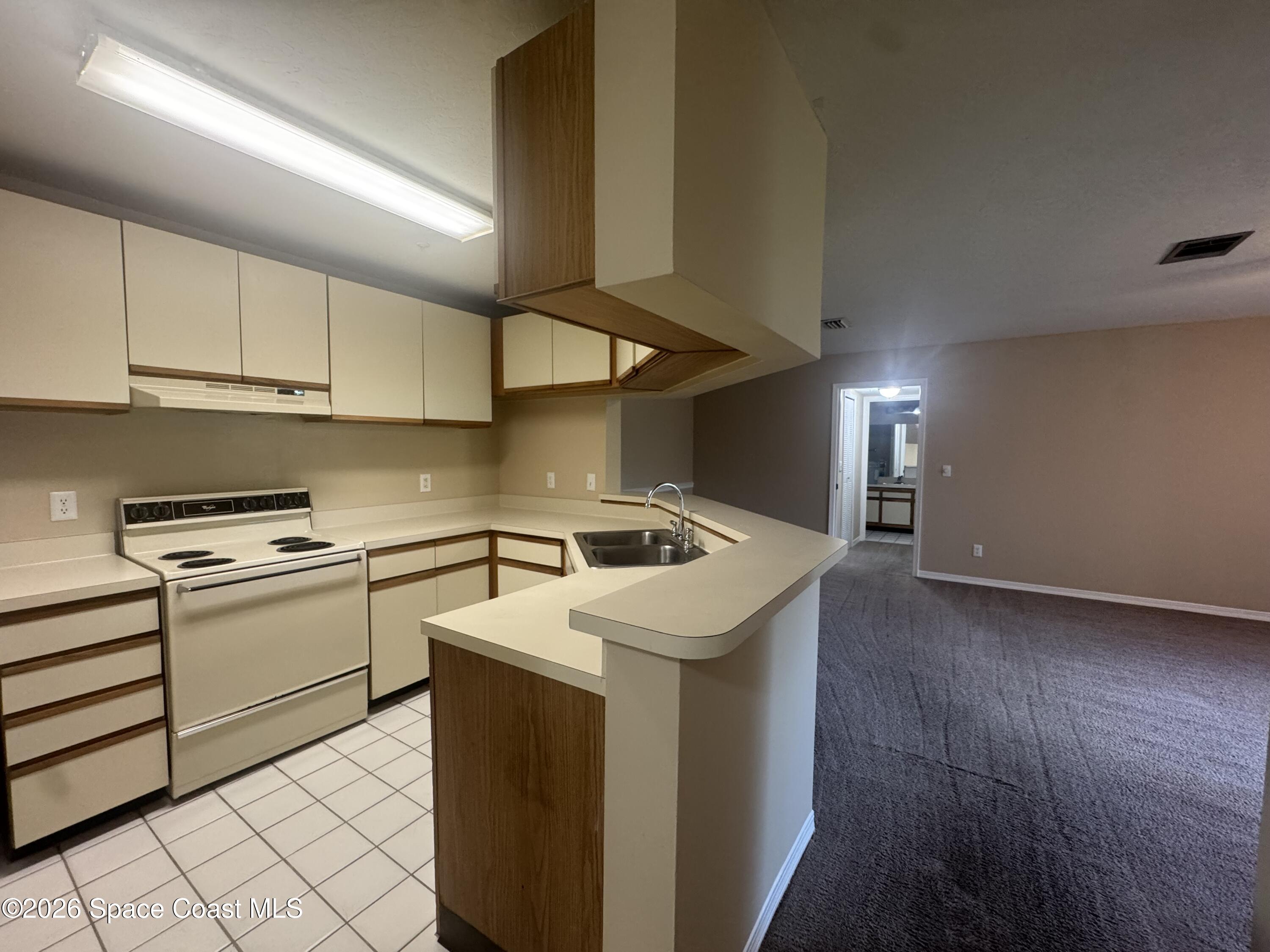 7667 North Wickham Road, Unit 1107 Melbourne, FL 32940 - Photo 7 of 19 a kitchen with a sink a stove and cabinets