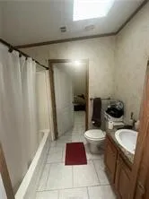 a bathroom with a sink a toilet a shower and a window