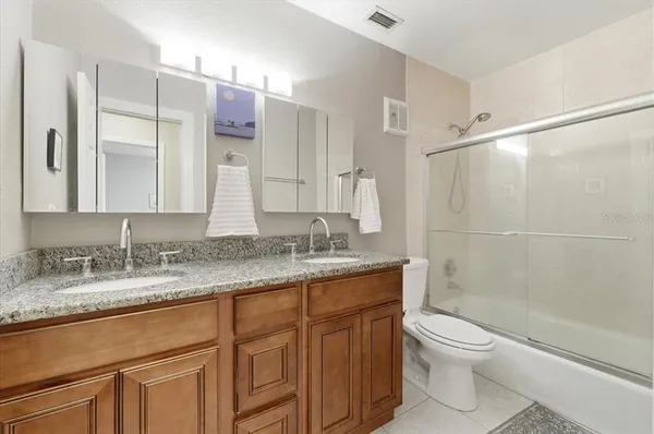 a bathroom with a granite countertop toilet sink and mirror