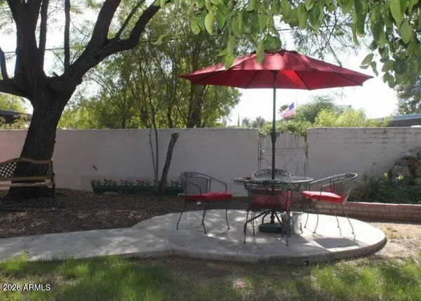 a patio with table and chairs under an umbrella