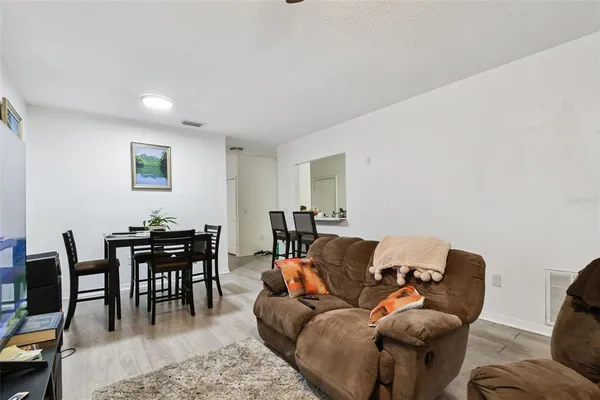 a living room with furniture a dining table and a piano next to a window
