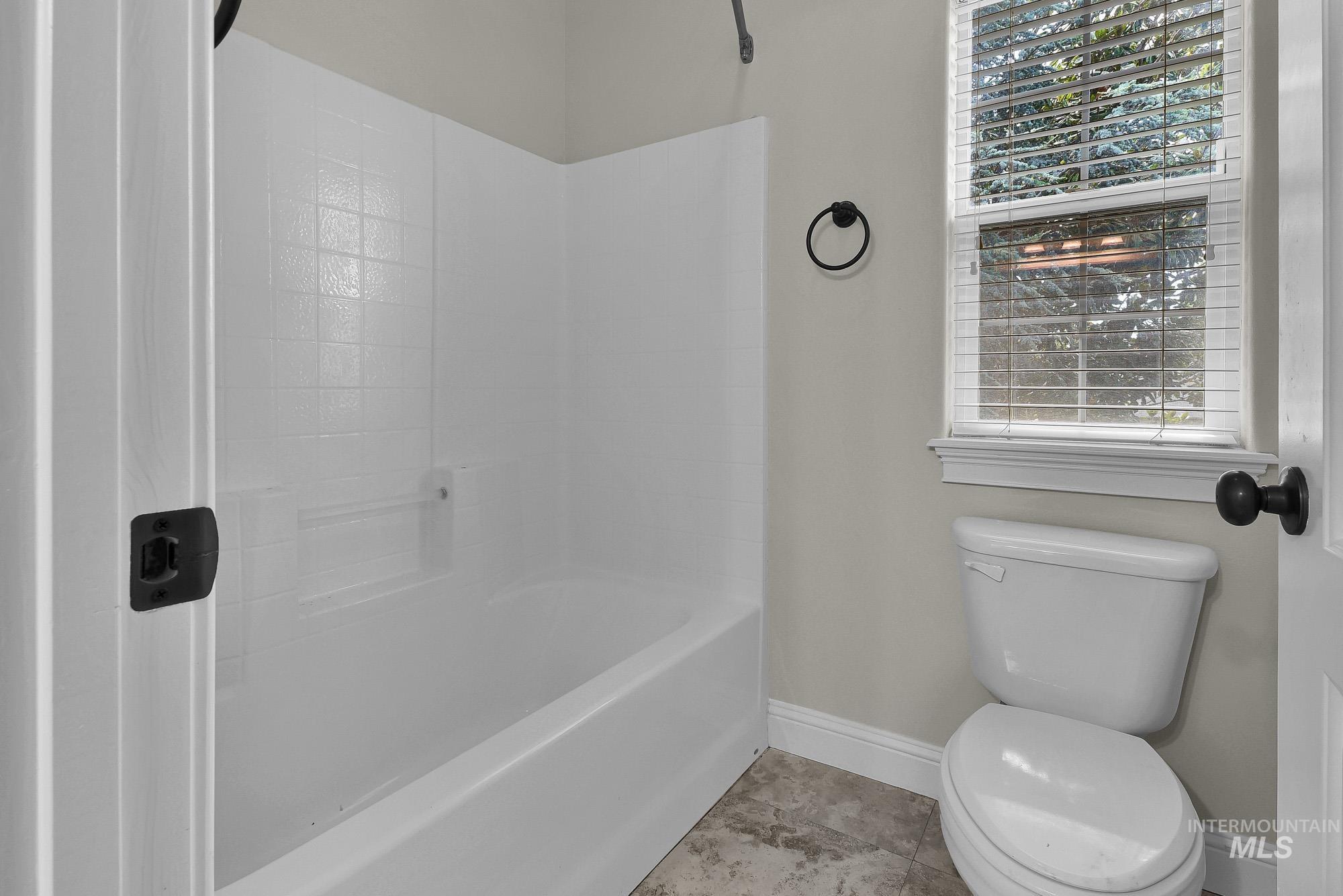 2172 West Cedar Grove Street Meridian, ID 83646 - Photo 35 of 49 Bathroom featuring a white tub-shower combination with integrated shelving, a white toilet, and neutral-toned wall paint