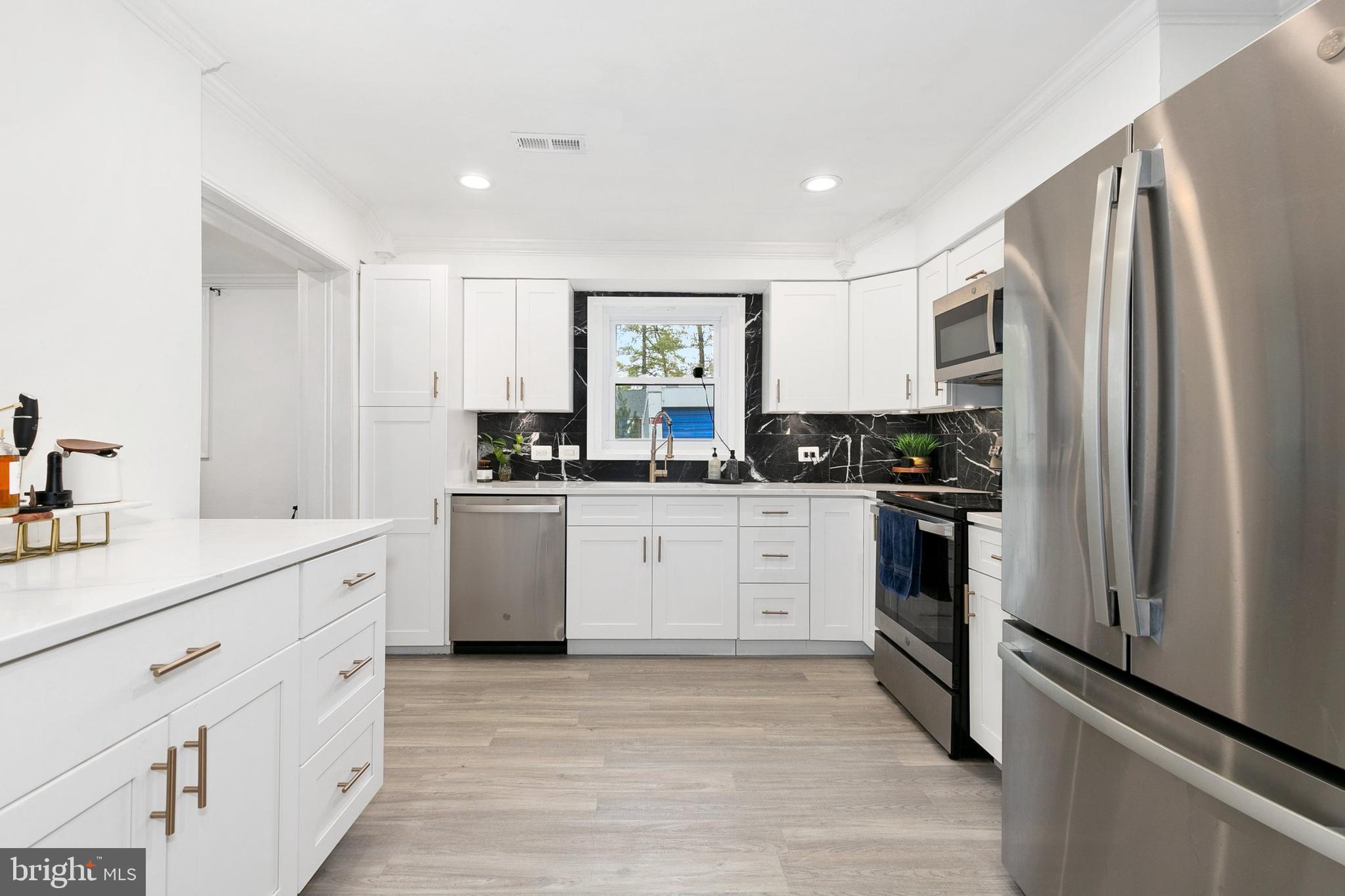 2920 Weisman Road Silver Spring, MD 20902 - Photo 8 of 32 a kitchen with white cabinets and stainless steel appliances