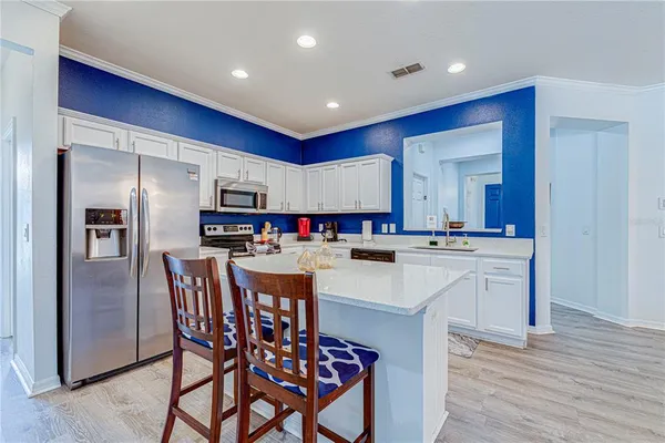 a kitchen with stainless steel appliances a sink a stove a refrigerator cabinets and a dining table