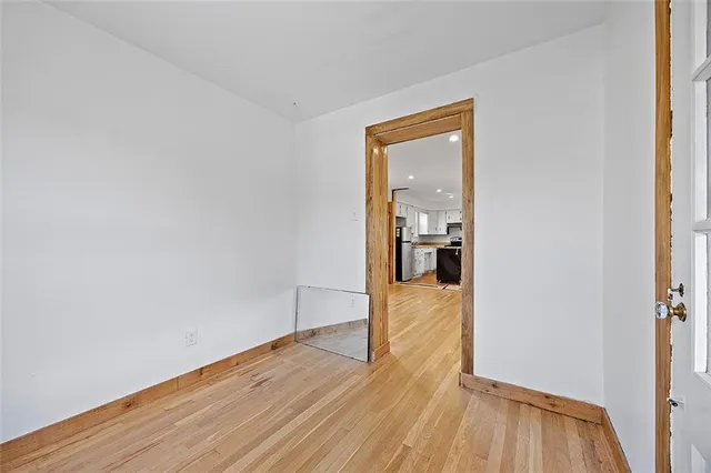 a view of a hallway with wooden floor and a bathroom