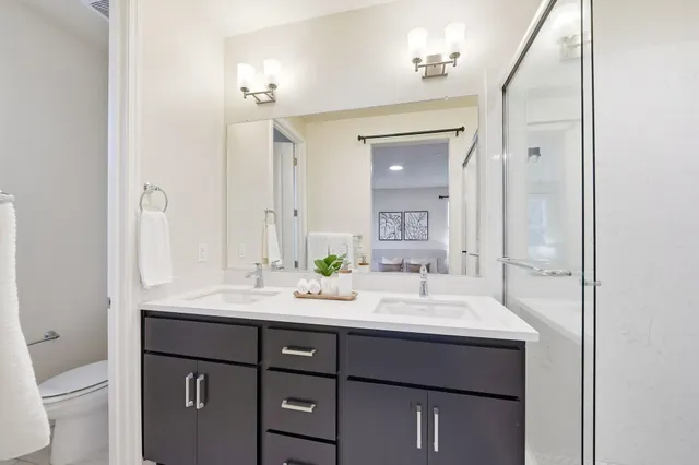 a bathroom with a granite countertop shower sink vanity and a mirror