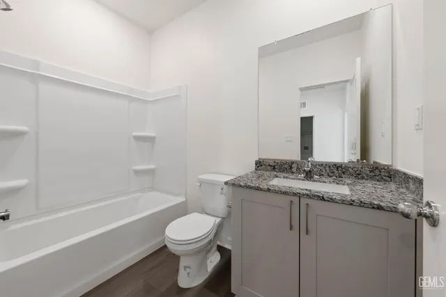 a bathroom with a granite countertop toilet sink and mirror