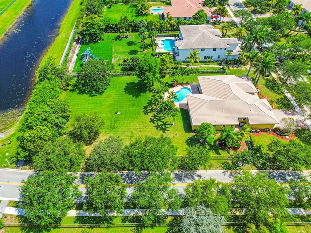 an aerial view of a houses with a garden and lake view